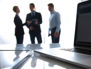 Focus on laptop on the table. Blurred people on background