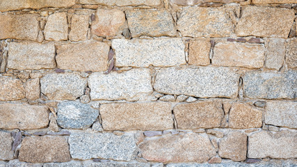 Detail of an old stone wall arranged in an irregular manner. Architecture constructions. Vintage background.