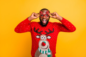 Portrait of his he nice attractive stylish cheerful cheery glad funky guy wearing cool winter Santa look outfit style touching specs isolated over bright vivid shine yellow background