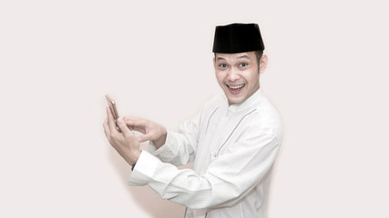 portrait of Funny an asian muslim man with head cap taking a call