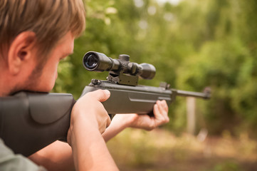 Concept of shooting, hunting close-up. A man shoots from a pneumatic weapon in nature close-up. Air rifle parts and copy space.