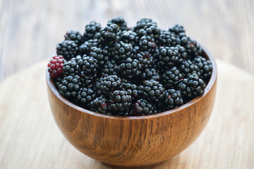 Sweet blackberry in wooden bowl on wooden table