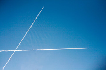 Two airplanes crossing vapor trails in blue sky