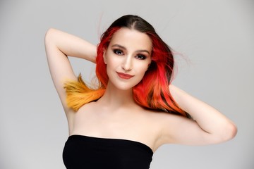 Fototapeta premium Studio portrait of a model with perfect makeup and colored hair on a white background. Beautiful female face of a pretty girl. Perfect makeup. Skin care. Fashionable cosmetics.