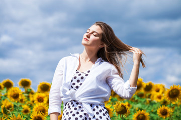 Portrait of a young beautiful girl in a field of sunflowers