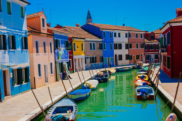Fototapeta na wymiar Colorful houses along a green canal with old boats in Burano Italy