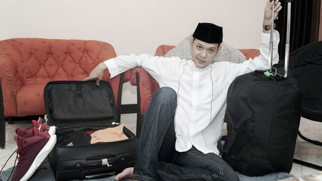 Handsome Muslim Asian Man With Traditonal Songkok Or Head Cap Prepare Suitcase Luggage For Eid Mubarak Holiday