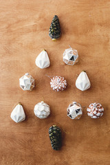 Christmas vintage ornaments in shape of christmas tree on wooden background, flat lay. Stylish vintage glass baubles and pine cones, scandinavian minimal style. Merry Christmas