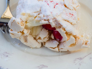 Meringue cake "Pavlova" with fresh ripe strawberry and whipped cream on a white plate