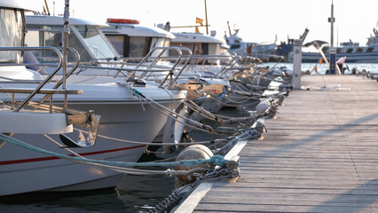 View on the swing moorings and pile moorings of the boats in the port. Moored small motorboats at the dock at summer time. Quays, wharfs, jetties, piers.