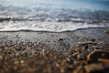 Fototapeta na wymiar Sea waves of the blue sea with foam roll ashore the golden shore. Close-up
