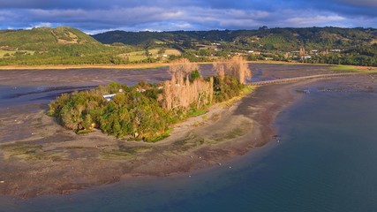 Fototapeta na wymiar Aerial view with drone of the iconic Aucar Island that has a bridge made of wood. This island that is near the town of Quemchi in the Chiloé archipelago 