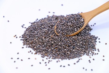 Wooden spoon full of Chia seeds on pile of Chia seeds isolate on white background.