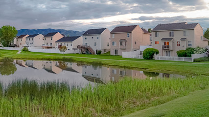 Panorama Shiny pond with bridge on a grassy park in front of lovely homes with balconies