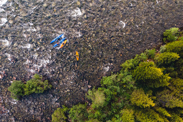 Extreme sportsmen are kayaking and rafting on mountain river in forest. Aerial top view