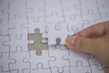 Business solutions and success concept. Businessman hand connecting jigsaw puzzle.