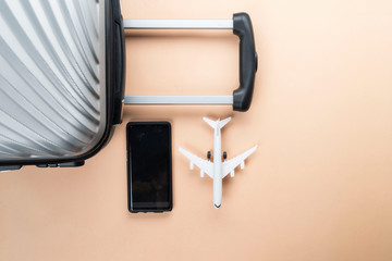 Flat lay grey suitcase with phone and mini airplane on pastel background. travel concept - Image