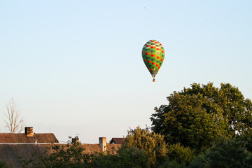 Fototapeta na wymiar Beautiful view of clear sky with colorful baloon flying over a small countryside city.