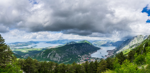 Montenegro, XXL panorama view above kotor bay city houses, waterside and harbor with two cruise ships seen from above tree tops of mountains