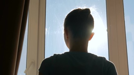 Woman silhouette opening curtains and looking out of window in hotel room at morning. Sun lens flare