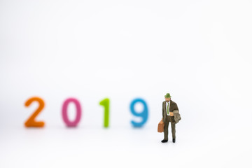 2019 planning concept. Close up of businessman miniature figure with handbag and jacket on white background white colorful plastic number with copy space