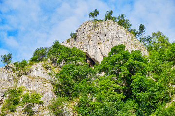 High rock wall with cave, where multi-pitch climbing routes and via ferrata route Dragons Amphitheater are built, in Parang mountains, near Womens Cave (Pestera Muierilor), Baia de Fier, Romania.