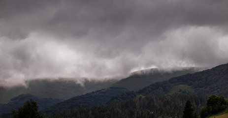 Heavy stormy clouds over green mountain slopes at Carpathian mountains. Ukraine.