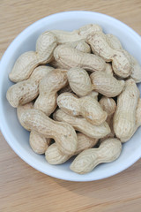 Peanuts in nutshell in a bowl on wooden table