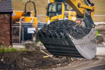 A digger and dump truck move dirt to make room for the foundations of the new Waverley School in Sheffield, South Yorkshire, UK