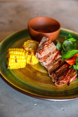 tasty and delicious grilled meat lies on a plate with spinach and tomato corn in a restaurant