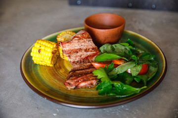 tasty and delicious grilled meat lies on a plate with spinach and tomato corn in a restaurant