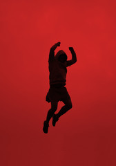 Fototapeta na wymiar A Silhouette of an athletic person jumping on red background