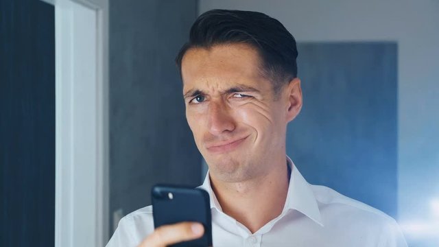 Portrait of shocked and disgusted man. Confused man saw an unpleasant message on a smartphone. He is worried about seeing. Close-up.