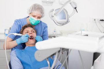 Male patient sitting on chair in dental office getting dentist treatment