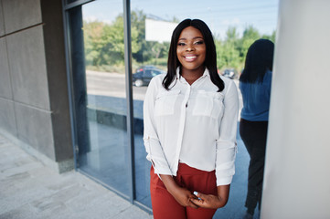 Formally dressed african american business woman in white blouse and red trousers. Successful dark...