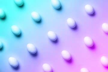 Food concept with white chicken eggs in trendy neon colors. Rainbow gradient background. Top view. Creative pattern in minimal style. Flat lay.