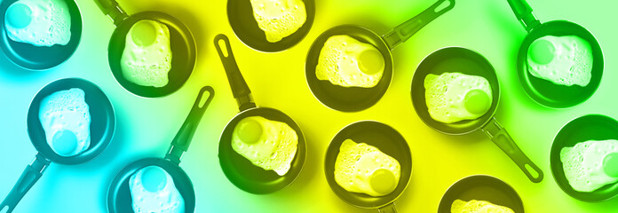 Creative food pattern with fried eggs on pans in trendy neon colors. Rainbow gradient background. Top view.
