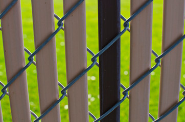 A view of the plastic strips as they sit in the chain linked fence at the park. 