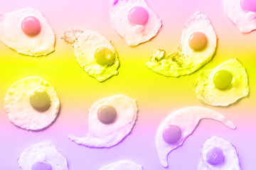 Fried eggs or scrambled eggs pattern in trendy neon colors. Rainbow gradient background with copy space. Creative food concept. Top view. Banner