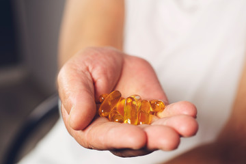 Old woman hand holding an Omega 3 fish oil capsules