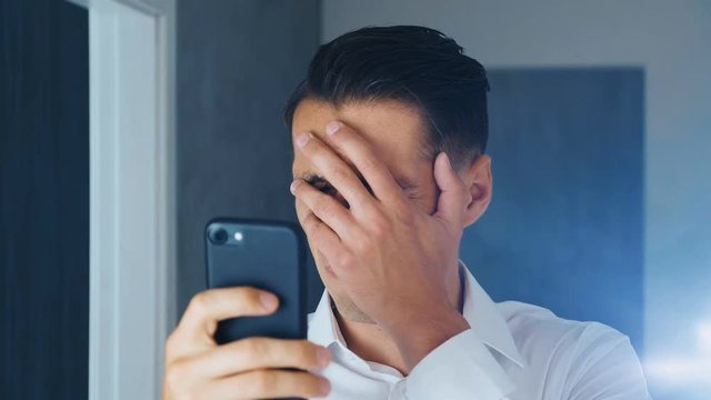 Portrait of shocked and disgusted man. Confused man saw an unpleasant message on a smartphone. He is worried about seeing. Close-up.