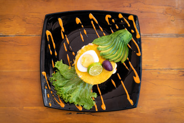 Traditional Peruvian dish called Causa Limeña made with mashed potatoes, vegetables, avocado and...