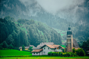 Swiss landscape, houses and church on green alps meadow