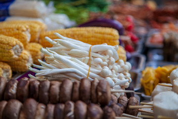 Asian food on the street, grilled corn, mushrooms on skewers, dried cheese