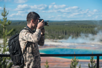 Obraz premium Tourist man taking photos and enjoy the view of geysers in Yellowstone National Park