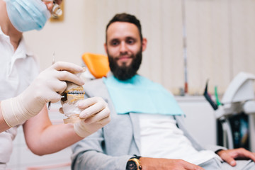 Сheerful handsome bearded man smiling to the camera sitting in a dental chair. Dentist and patient in dentist office. Amazing smile!