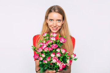 It's so sweet! Cute lovely portrait of blonde woman with large bouquet of roses while she looks on camera. Holidays and gifts concept. Women's day