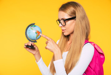 Fototapeta premium Study, education, university, college, graduate concept on yellow background. Portrait of beautiful smiling blonde woman. Young student with backpack