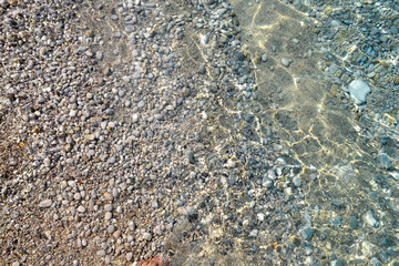 Clear sea water texture, top view of the rocky bottom. Transparent tropical ocean, coral reefs, abstract emerald water surface background