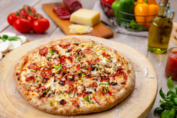 Delicious homemade style supreme vegetable and meat pizza in restaurant kitchen with full ingredients